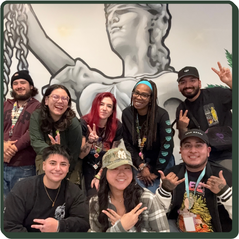 A photo of some of our retail team posing in front of a lady Themis mural