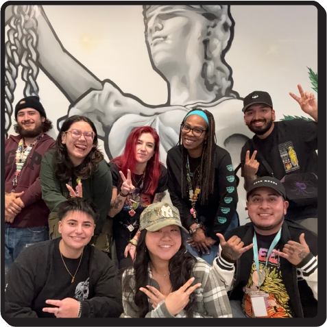 A photo of some of our retail team posing in front of a lady Themis mural